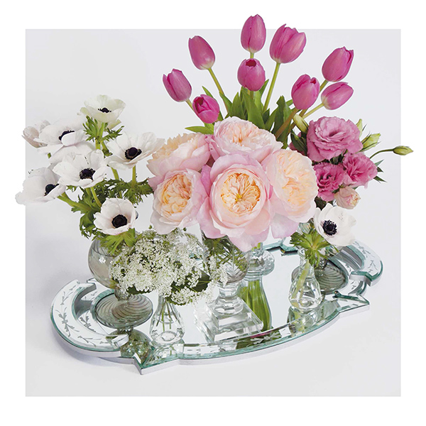 Centerpiece with gathered bunches of flowers in bud vases.