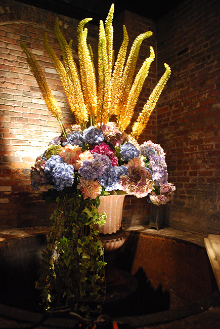 An urn holds a large arrangement with faux hydrangeas