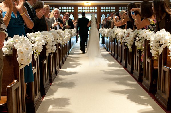 Phalaenopsis orchids draped over pews.