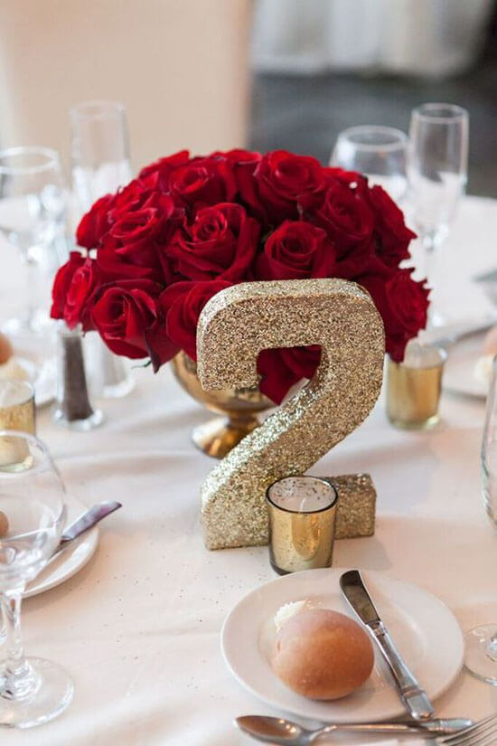 a glittery 2 table number next to a classic dome of red roses
