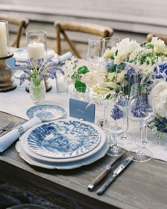 blue place cards on long reception table set with blue table linens and plates