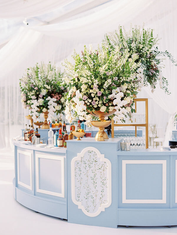 periwinkle blue custom wedding reception bar with towering florals