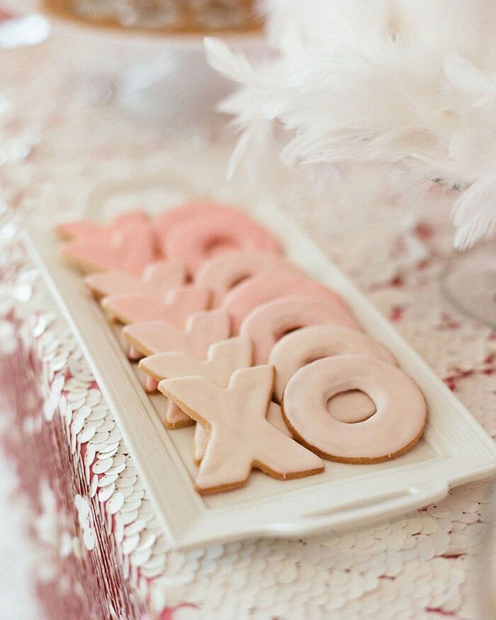 X O pink glazed cookies on a white ceramic tray