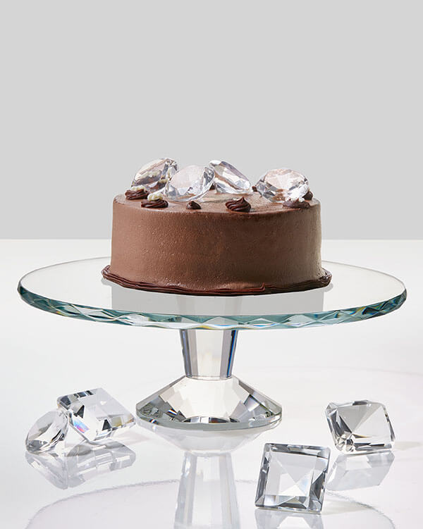 chocolate cake topped with large crystal diamonds displayed on crystal cake plate