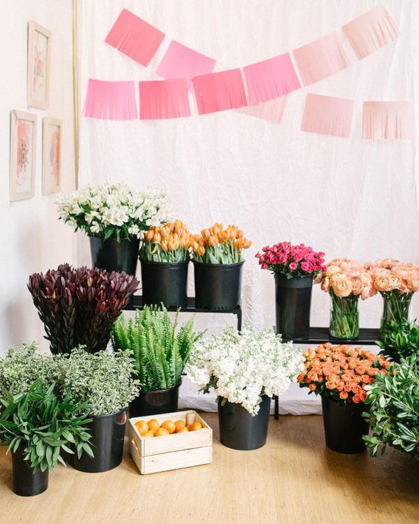 diy bouquet station with black flower buckets on tables holding tulips rose and ranunculus