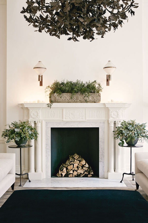 modern christmas home with greenery arrangements around fireplace