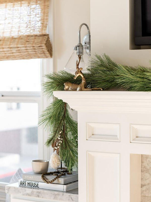neutral classic christmas holiday home decor idea, a white mantel with white pine garland and a gold reindeer sculpture 
